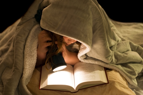 A young girl reading a book under the covers with a flashlight; Shutterstock ID 25849123; PO: The Huffington Post; Job: The Huffington Post; Client: The Huffington Post; Other: The Huffington Post